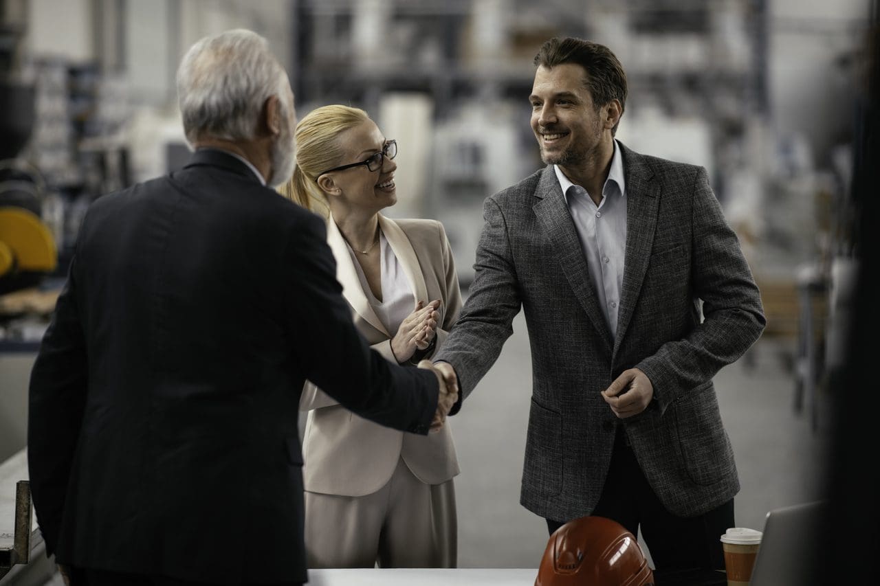 Businesspeople shaking hands in industrial workshop